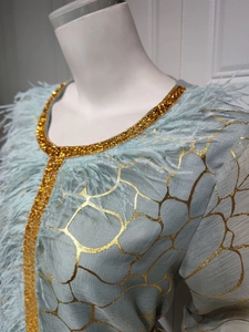 Detail von minzgrünem Kleid mit Goldfolientextur und luxuriösem Federkragen-Besatz