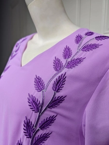 Macro detail of refined floral embroidery on the pink chiffon neckline of the dress