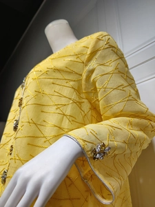 Close-up of bright yellow ethnic mesh dress with 3D embroidery and handmade beadwork