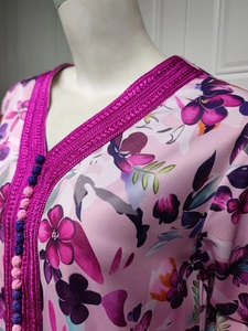 Detail of rose purple floral kaftan featuring woven lace trim and traditional buttons