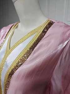 Detail of luxury pink satin gown with gold embroidery and gemstone beads at neckline
