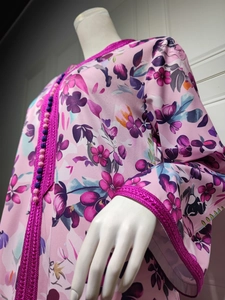 Detail of floral pink dress featuring ethnic woven trim and decorative ball buttons