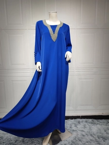 Detail von perlenbesetztem V-Ausschnitt und Zierknöpfen an einem blauen Maxikleid