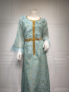 Detailaufnahme von hellblauem Kaftan-Kleid mit Goldfolie und blauen Federbesätzen
