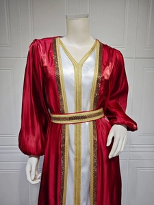 Detail of red satin dress with gold braided trim and sequins on white fabric