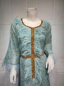 Detail des hellblauen Kleides mit goldenem Gittermuster und elegantem Federbesatz