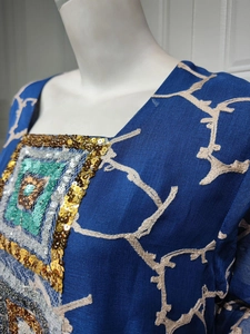 Close-up of geometric sequin embroidery and floral print on navy blue dress fabric