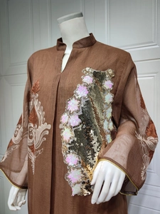 Nahaufnahme eines braunen Kaftans mit rosa-goldenen Pailletten und Stickereien