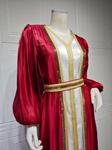 Detail of luxury red satin caftan featuring intricate gold embroidery and rhinestone accents