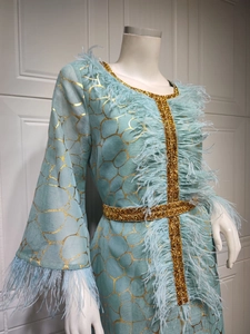 Detail des hellblauen Kleides mit goldenem Gitterdruck und luxuriösem Straußenfederbesatz