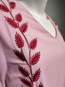 Detailed close-up of intricate gold and red leaf embroidery on a pink chiffon dress