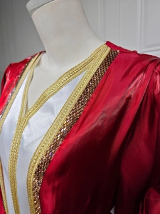 Close-up of luxury red and white kaftan dress with golden lace and sequin neck embroidery