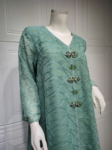 Close-up of green mesh embroidery dress featuring luxury gemstone buttons and V-neckline