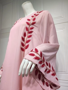 Detail of red leaf embroidery with gold edges on a pink chiffon long-sleeved dress
