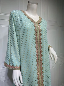 Detail eines hellblauen Kaftans mit Goldfolienmustern und aufwendiger Paillettenstickerei