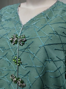 Detailed embroidery on green mesh fabric with silver piping and sparkling crystal beads