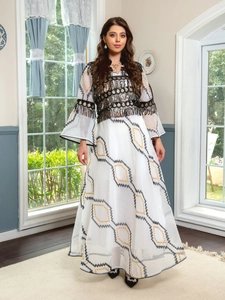 Close-up of ethnic white maxi dress with sequined embroidery and layered metal tassels