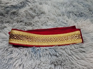 Detailed view of red ethnic garment belt with gold embroidery and brown sequins texture