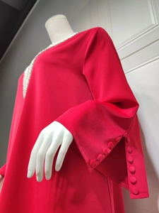 Detail eines roten Chiffonkleides mit Strassausschnitt und Schlitzmanschetten mit Stoffknöpfen