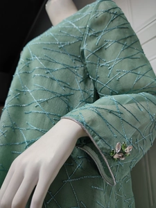 Detail of mesh embroidery on long sleeves with beaded floral accents and silver trim