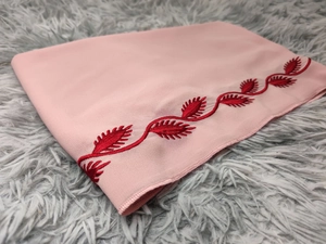Detail of pink chiffon scarf with intricate red vine embroidery on plush background