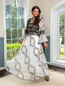 Close-up of white evening dress featuring black tassels, sequins and geometric embroidery