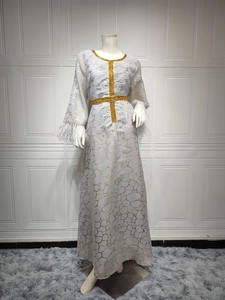 Detail eines weißen Kaftans mit goldenem Foliendruck und Federn an den Ärmelbündchen