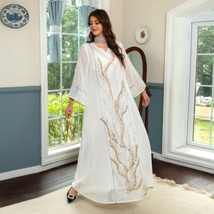 Detail shot of white long-sleeved maxi dress featuring gold and silver sequin embroidery