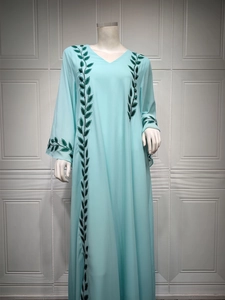 Close-up of intricate green vine embroidery and V-neckline detail on the pink maxi dress
