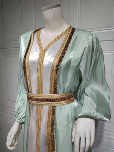 Detail of mint green satin kaftan featuring intricate gold beaded embroidery and lantern sleeves