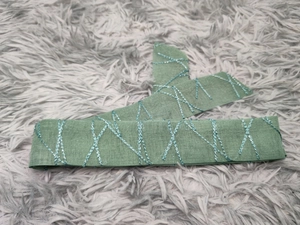 Detailed view of green mesh embroidery fabric with shiny silver cross-stitch patterns