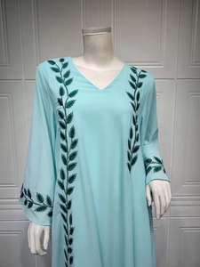 Detail of leaf embroidery and V-neckline on light blue long-sleeved ethnic dress