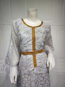 Detail der Goldpailletten-Stickerei und weißem Federbesatz am grauen Kleid