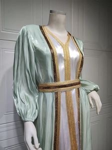 Detail of mint green satin evening gown featuring intricate gold beaded embroidery patterns