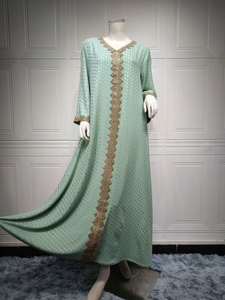 Detail eines mintgrünen Kaftans mit goldenen Folienpunkten und Perlenstickerei