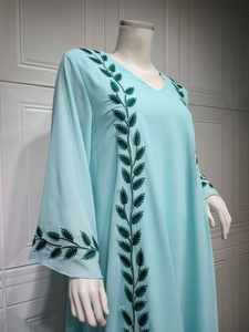 Detailed view of green leaf embroidery on the neckline of a light blue chiffon dress