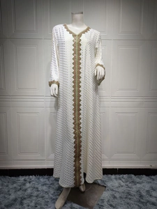Detailansicht eines weißen Kaftans mit goldenem Punktdruck und olivgrüner Stickerei