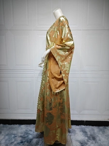 Detail view of long-sleeve orange kaftan with metallic gold foil textures and woven lace trim