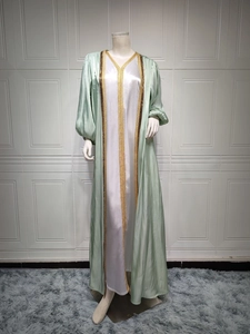Detail of light green satin abaya with intricate gold sequin embroidery and beaded trim