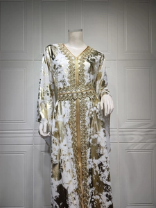 Close-up of golden embroidery and bronzing patterns on a white chiffon kaftan dress