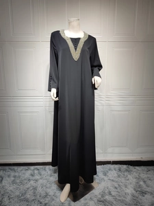 Detail eines handperlierten V-Ausschnitts mit Gold- und Silberperlen auf einer schwarzen Abaya