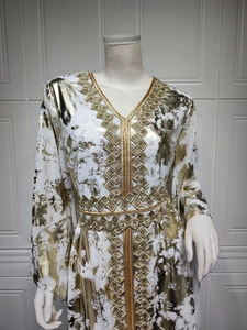 Detail view of V-neckline featuring golden geometric embroidery and metallic marble print