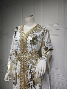Detail of white chiffon kaftan dress featuring gold foil patterns and embroidered neckline