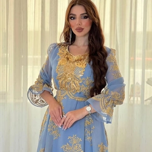 Detail of light blue dress featuring intricate gold floral embroidery and ruffled cuffs
