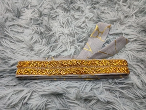 Detail von Goldmarmor-Muster und Metall-Nietenverzierung an einem Kleidergürtel