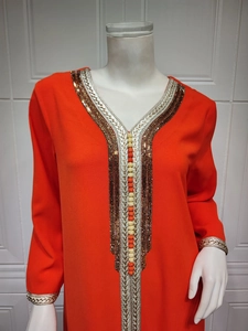 Detail of V-neckline with intricate gold embroidery and beadwork on orange kaftan
