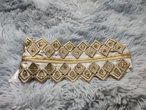 Detailed close-up of golden embroidery lace with sequins and geometric diamond patterns
