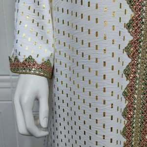 Detailansicht eines weißen Kleides mit Goldfolienprint und bunter Paillettenstickerei