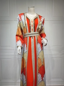Close-up of golden embroidery and sequin craftsmanship on a long sleeve orange kaftan dress