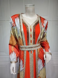 Detail of orange kaftan featuring intricate gold sequin embroidery and feather print